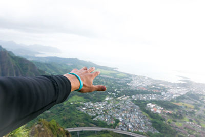 Cropped hand of man reaching towards city