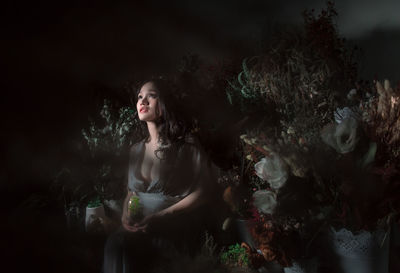 Pregnant woman sitting amidst plants at night
