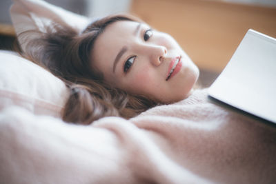 Portrait of young woman lying on bed at home
