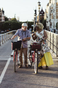 Senior couple with bicycle on bridge during weekend