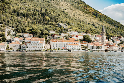 River by buildings and mountains against sky