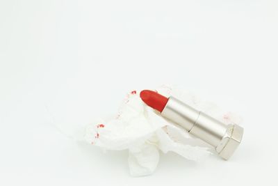 High angle view of red lipstick with tissue paper on white background