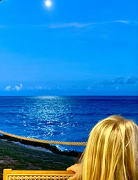 Rear view of woman looking at sea against blue sky