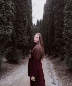 Portrait of woman standing against trees