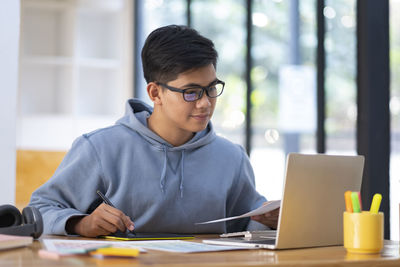 Young collage student using computer and mobile device studying online