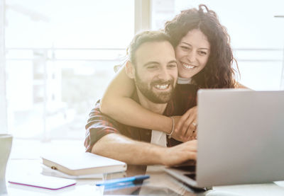 Portrait of smiling young woman using smart phone on table