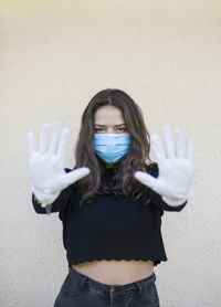 Portrait of young woman standing against wall