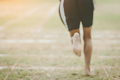 Low section of man walking on field