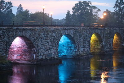 Arch bridge over river against sky during sunset