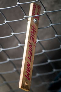 High angle view of text on wood in chainlink fence