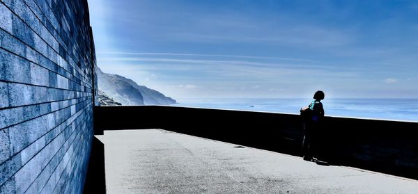 Man standing by sea against blue sky