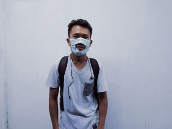 Portrait of young man standing against white wall