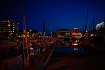 Sailboats moored at harbor against clear sky at night