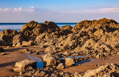 Scenic view of rocks on beach against sky