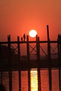 Silhouette man and child on u bein bridge over river during sunset
