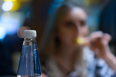 Close-up of bottle against woman in restaurant