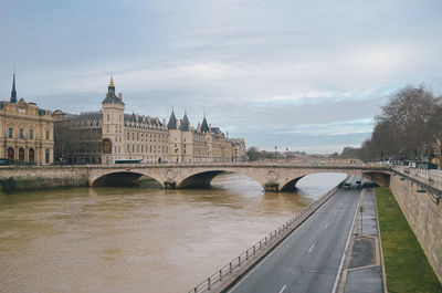 Arch bridge over river against sky in city