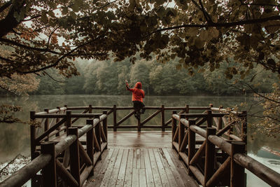 Man standing on footbridge by pier against trees