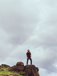 Man standing on rock against sky