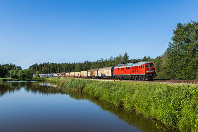 Train by trees against clear blue sky