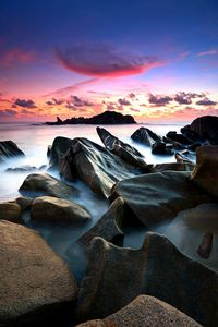 Rocks in sea against sky during sunrise