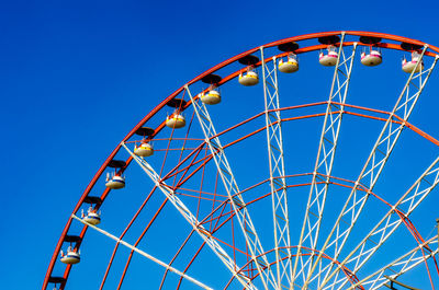 Low angle view of ferris wheel against clear blue sky