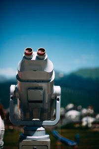 Close-up of coin-operated binoculars against blue sky