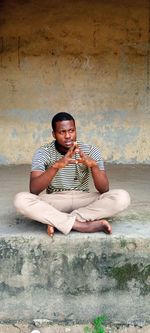 Portrait of young man sitting on footpath