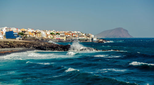 Scenic view of sea and cityscape against clear sky