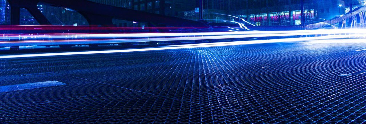 LIGHT TRAILS ON ROAD AGAINST BLUE SKY