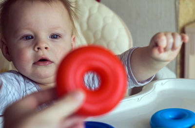 Cropped image of mother playing with cute son on high chair at home