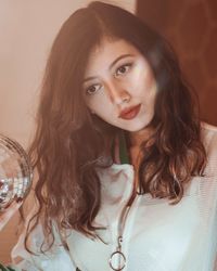 Thoughtful young woman holding disco ball while looking away