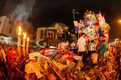 Crowd at illuminated market stall in city at night