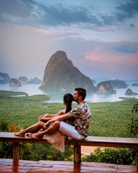 Couple sitting against rock formations and sea