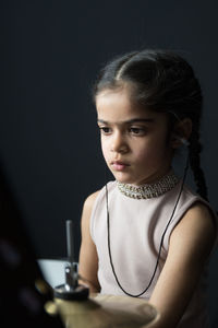 Girl wearing hearing aid while playing drum against wall