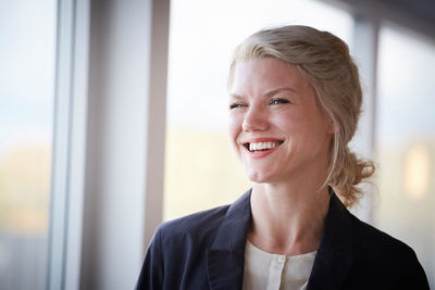 Smiling confident businesswoman looking away at workplace