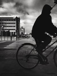 Silhouette man riding bicycle on street