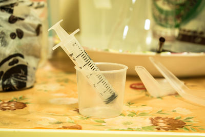 Close-up of syringe in plastic container on table