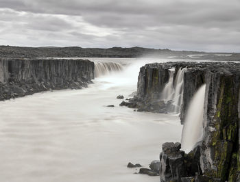 Scenic view of waterfall against sky