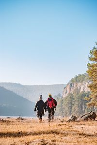 Couple walking on field against mountains