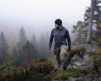 Hiker walking on mountain against sky during foggy weather