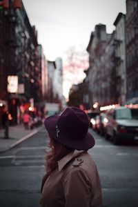 Rear view of woman on road against sky in city