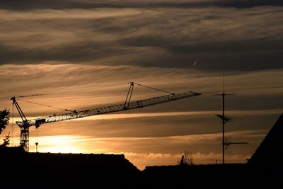 Low angle view of silhouette cranes against sky during sunset