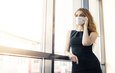 Portrait of woman standing against window