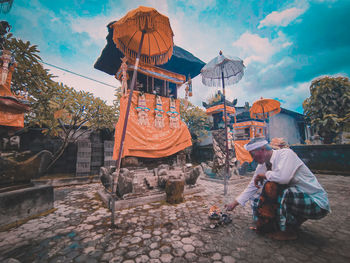 Rear view of men sitting on temple against sky