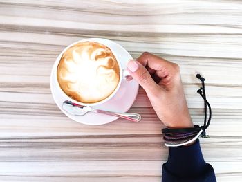 High angle view of hand with cappuccino cup