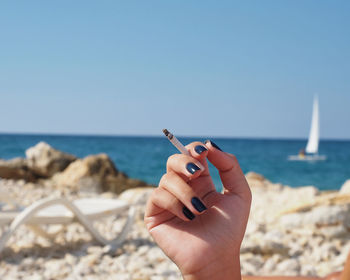 Person holding umbrella on beach against clear sky