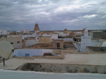 Houses in town against cloudy sky