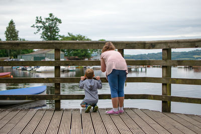 Rear view of children on pier against river