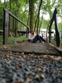 Man sitting on swing in forest